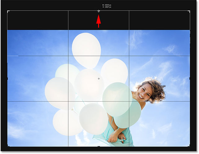 Dragging the crop handle upward to add more space above the photo in Photoshop